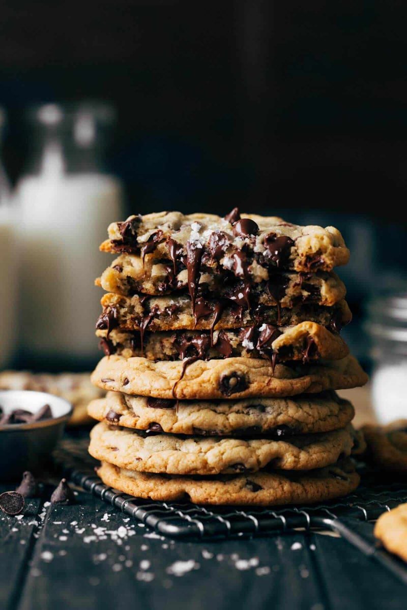 A tall stack of chocolate chip cookies with melted chocolate and flaky salt
